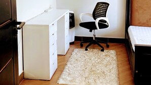A bedroom with a bed, a desk, a chair, and a fluffy rug. - Charming 1-bedroom apartment with City View in lively Kampala (Kampala)