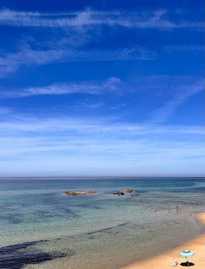 A beach with clear water, a sandy shore, and a few people in the distance. - Affittimoderni Castelsardo - Casa Marittima (Castelsardo)