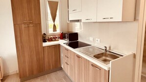 A compact kitchen with wooden cabinets, a built-in microwave, and a stainless steel sink. - Affittimoderni Castelsardo - Casa Marittima (Castelsardo)