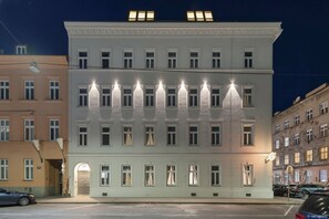 Ein mehrgeschossiges Gebäude mit einer symmetrischen Fassade, gleichmäßig angeordneten Fenstern und einem zentralen Eingang.
