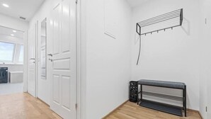 Um corredor com portas brancas, um radiador e um banco preto.