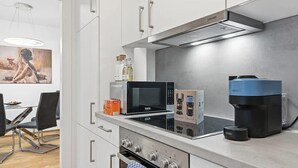 Ett modernt kök med inbyggd ugn, mikrovågsugn och kaffebryggare.