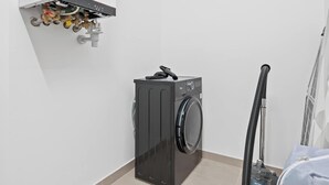 Ett tvättrum med tvättmaskin, dammsugare och varmvattenberedare.