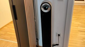 Una habitación moderna y minimalista con un calefactor vertical, un radiador y un enchufe en la pared.