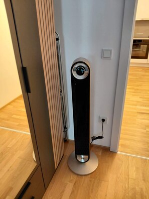 Ein modernes, minimalistisches Zimmer mit Heizlüfter, Radiator und Steckdose an der Wand.