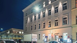 Un edificio de varios pisos con ventanas iluminadas y una calle en su parte frontal.