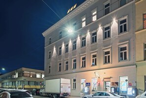 Ein mehrstöckiges Gebäude mit beleuchteten Fenstern und einer Straße davor.