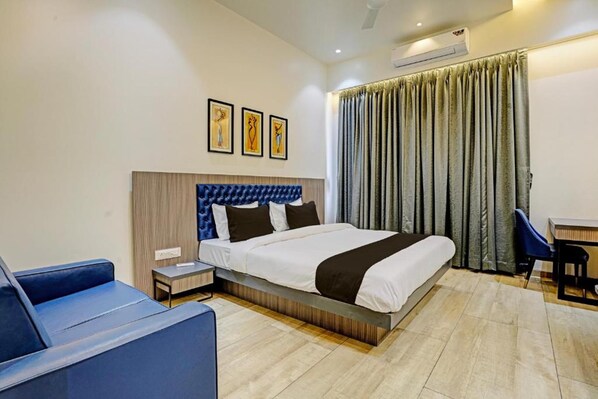 Een hotelkamer met een bed, een bureau, een stoel, een klein tafeltje en een airconditioning.
