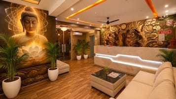 Un vestíbulo de hotel con un mural de Buda, una recepción y una zona de estar.