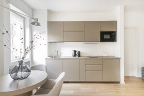 Una cocina moderna con microondas integrado, cafetera y un florero con flores secas sobre la encimera.