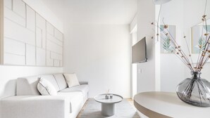 Ein modernes Wohnzimmer mit einer Couch, einem runden Couchtisch, einem Flachbildfernseher und einer dekorativen Vase.