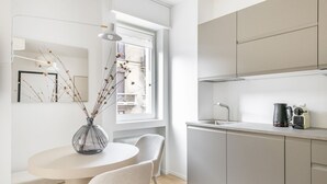Eine moderne Küche mit Fenster, einem Esstisch mit Stühlen und einer Kaffeemaschine.