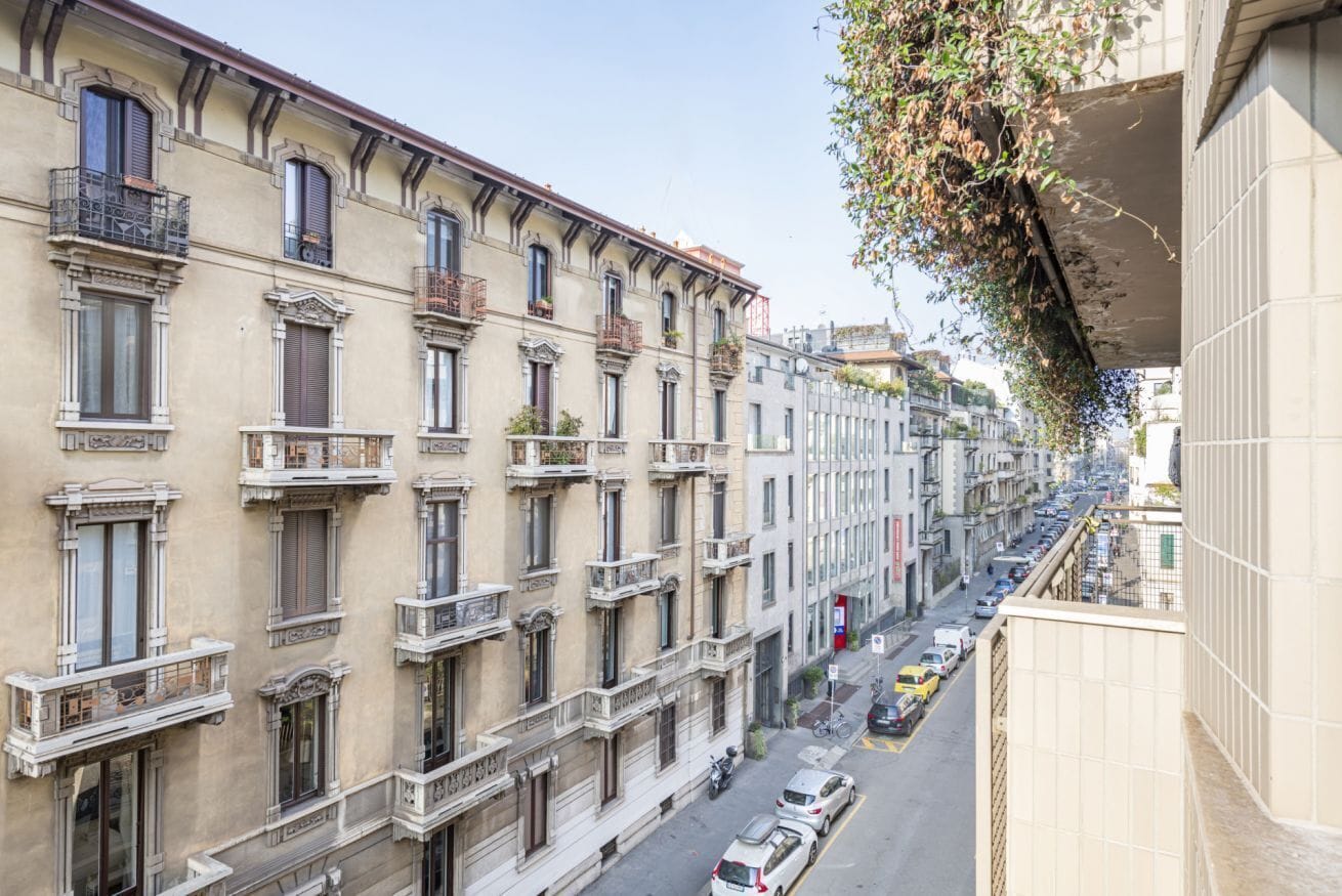 A multi-story building with balconies, a street below, and a clear sky.