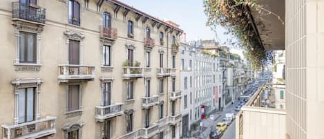 Un edificio de varios pisos con balcones, una calle abajo y cielo despejado.