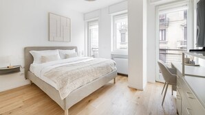 Ein modernes Schlafzimmer mit Bett, Schreibtisch und Blick auf die Stadt.