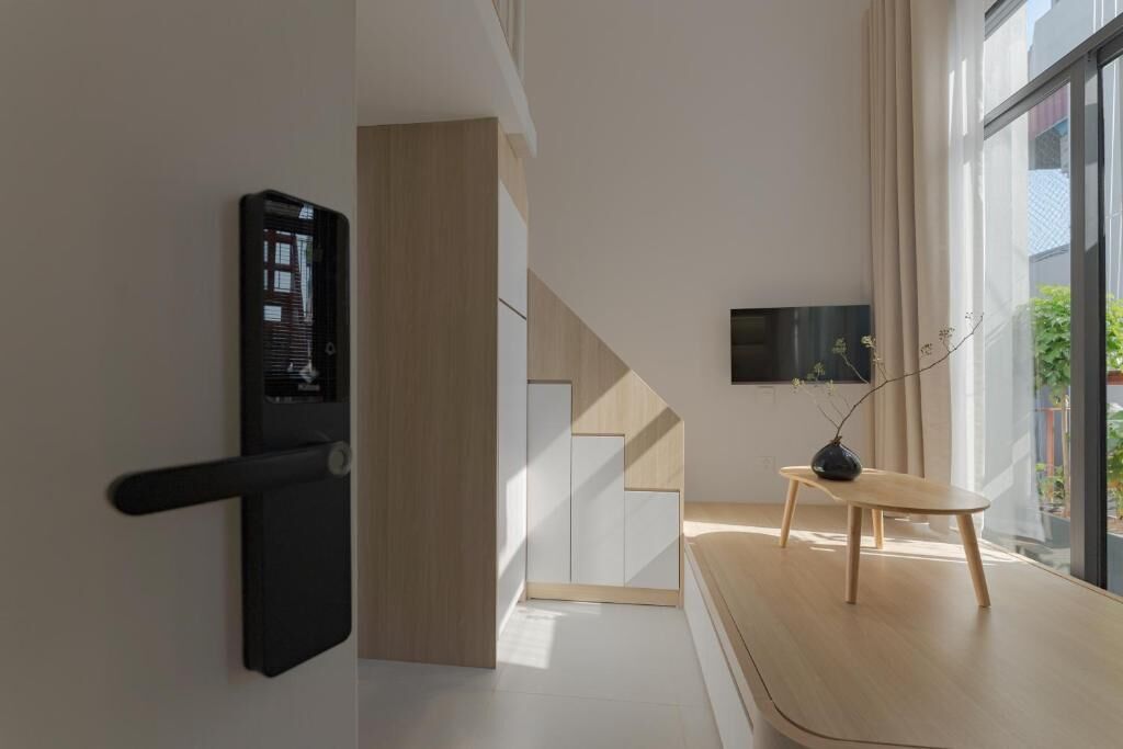 Ein modernes Interieur mit minimalistischem Design, mit einer schwarzen Tür, einer Holztreppe, einem Holztisch und einem an der Wand befestigten Fernseher.
