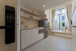 A modern kitchen with a built-in oven, a refrigerator, and a wall-mounted control panel. - YLiving Serviced Apartment  (Hanoi)