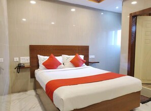 A hotel room with a large bed, a wooden headboard, a bedside table, and a phone on the nightstand.