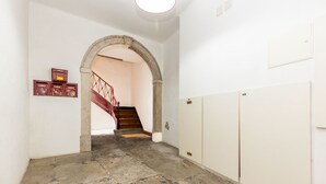 A hallway with a stone floor, a red staircase, and lockers on the right. - Charming 2 Bedroom Apartment at Bairro Alto (Lisboa)