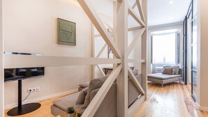 A modern living room with a flat-screen TV, a grey sofa, and a wooden floor. - Charming 2 Bedroom Apartment at Bairro Alto (Lisboa)