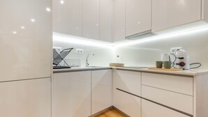 A modern kitchen with white cabinets, a wooden countertop, a coffee machine, and a kettle. - Charming 2 Bedroom Apartment at Bairro Alto (Lisboa)