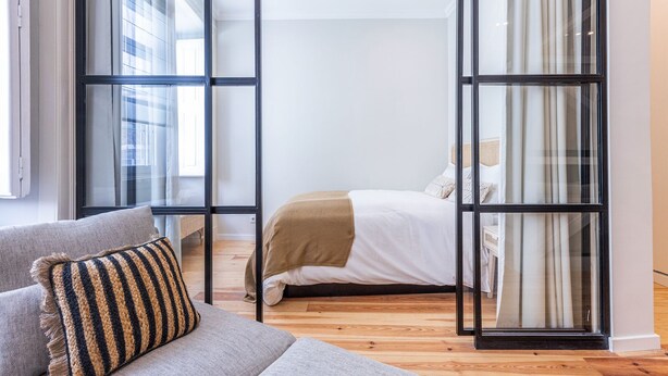 A modern bedroom with a bed, a sofa, and a glass partition. - Charming 2 Bedroom Apartment at Bairro Alto (Lisboa)