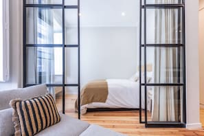 Een moderne slaapkamer met een bed, een bank en een glazen wand.