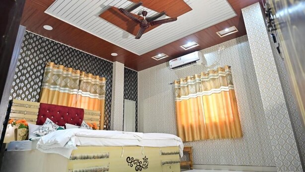 A bedroom with a bed, curtains, a ceiling fan, and an air conditioning unit.