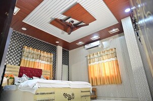 Un dormitorio con cama, cortinas, ventilador de techo y aire acondicionado.