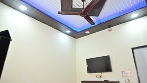A room with a ceiling fan, recessed lighting, a mounted TV, and a built-in shelf.
