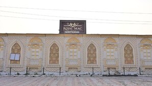 A building facade with a sign reading 'ROYAL MAC PALACE' and a series of arched windows with intricate lattice designs.