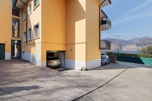 Ein Gebäude mit gelber Fassade, einer Garageneinfahrt und Blick auf Berge.