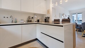 A modern kitchen with white cabinetry, a central island, and pendant lighting. - Lake View Casa di Sandra Apartment with Lake View, Wi-Fi, and Air Conditioning (Malcesine)