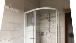 Uma casa de banho moderna com chuveiro em cabine de vidro, bidé e chão em mosaico.