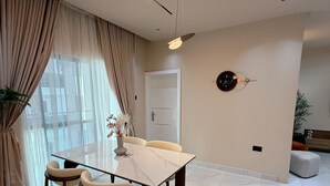 A modern dining area with a glass table, four chairs, a vase with flowers, and a ceiling fan. - L Rina Apartment (Lekki)