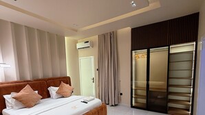 A modern bedroom with a large bed, a walk-in closet, and a sliding glass door. - L Rina Apartment (Lekki)