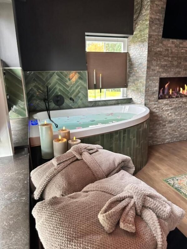 A spa room with a hot tub, candles, and a fireplace.