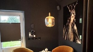 A modern room with two orange chairs, a round table with candles, a pendant light, and a large framed picture on the wall. - Wellness Tuin  Luxury Suites & Lodges (Horst)