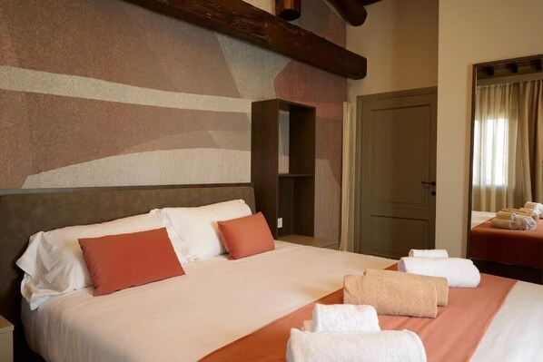 A hotel room with a large bed, a wooden headboard, a mirror, and a door.