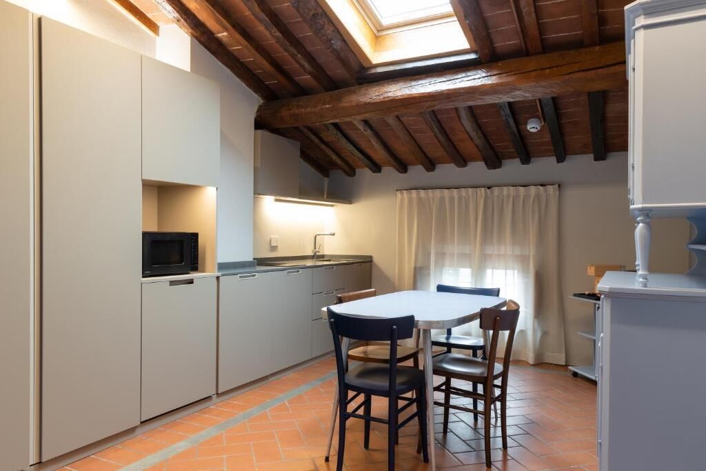 Une cuisine compacte avec un coin repas, un four à micro-ondes et une fenêtre avec des rideaux.