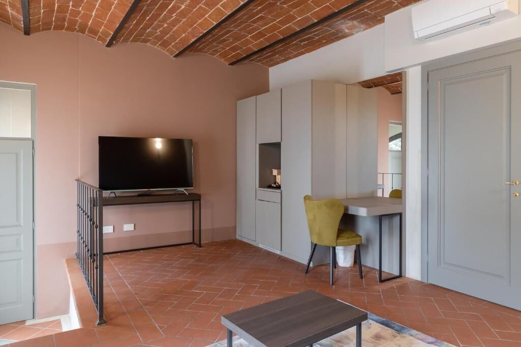 Ein Zimmer mit Fernseher auf einem Schrank, einem Schreibtisch mit Stuhl und einem Kleiderschrank.