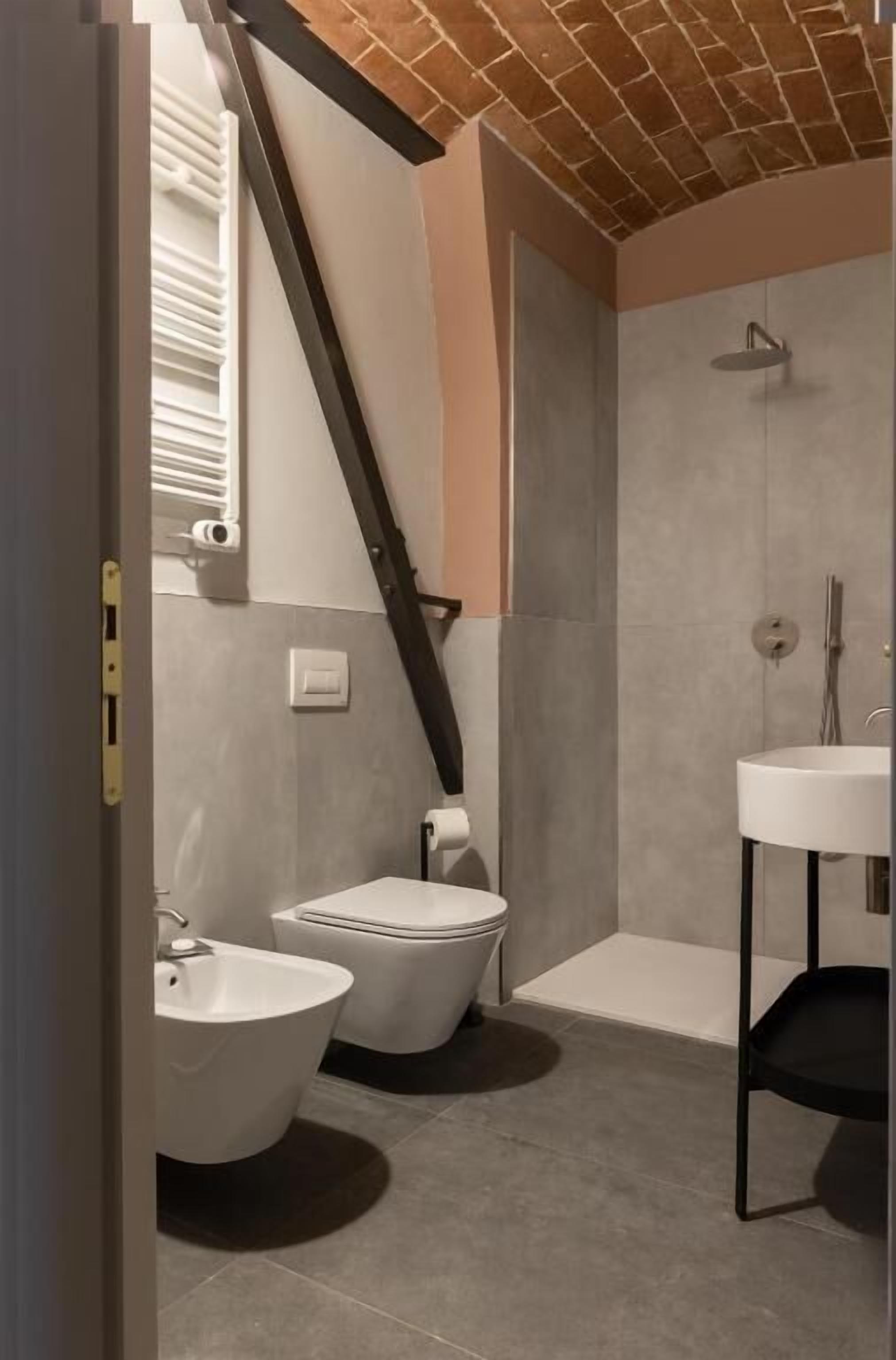 A modern bathroom with two toilets, a bidet, a shower, and a sink.