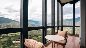 Un balcón con mesa y sillas, con vistas a un paisaje montañoso.