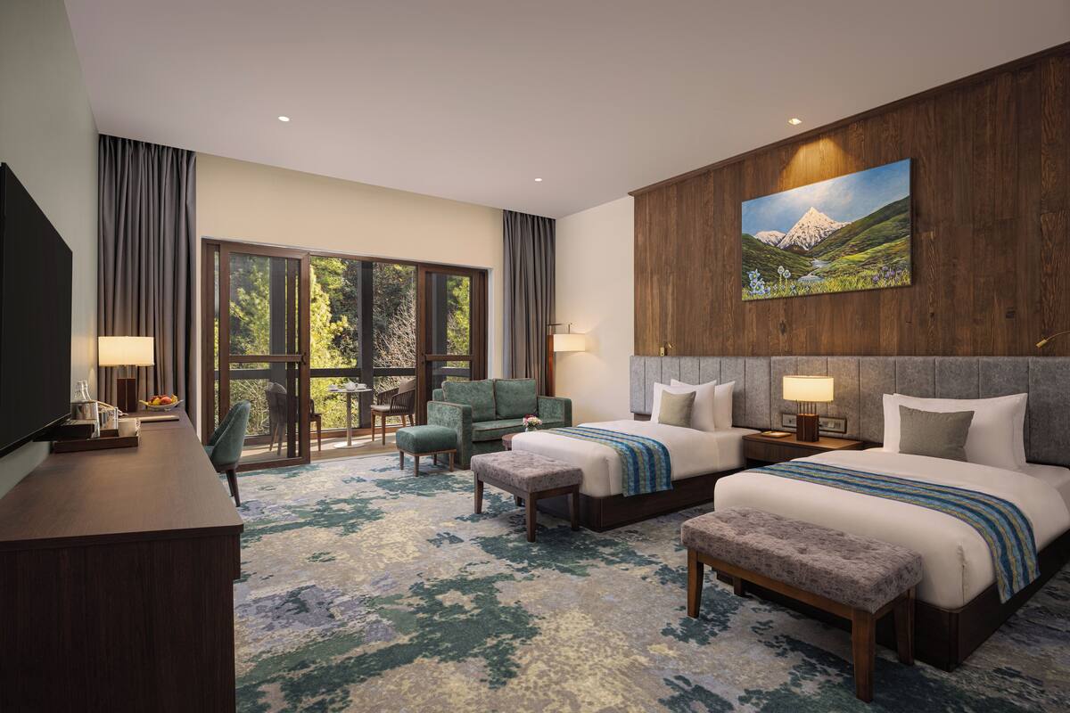 A hotel room with a large bed, two bedside tables, a desk, a chair, and a large window.