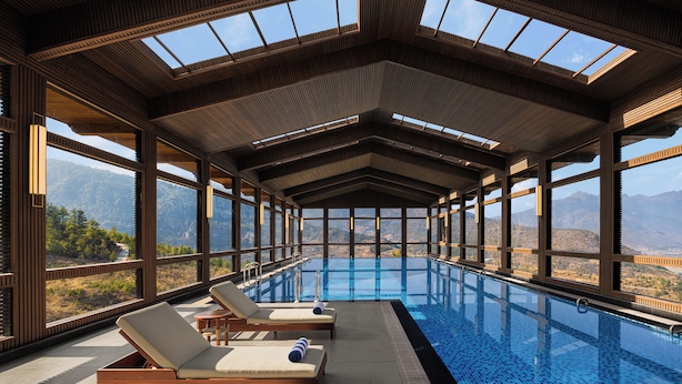 Una piscina interior con vigas de madera y ventanas amplias que ofrecen vistas a la montaña.