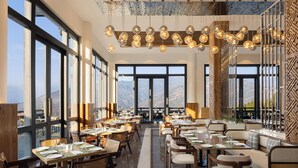 Un restaurante con amplios ventanales, varias mesas para comer y lámparas esféricas colgantes.