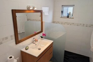 A bathroom with a white sink, a mirror, a towel, and a small window. - SeafrontView · Cozy T1 Apartment - 1 (Praia)