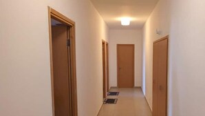 Un couloir avec des portes en bois, un sol carrelé et un luminaire au plafond.