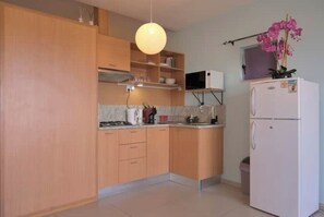 Eine Küche mit Holzausstattung, einem weißen Kühlschrank, einer Mikrowelle und einer Pendelleuchte.