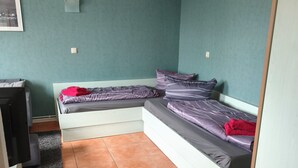 Een kamer met een bed, een bureau en een plafondventilator.